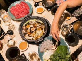Range of Japanese dishes and hotpot with a person reaching across with chopsticks