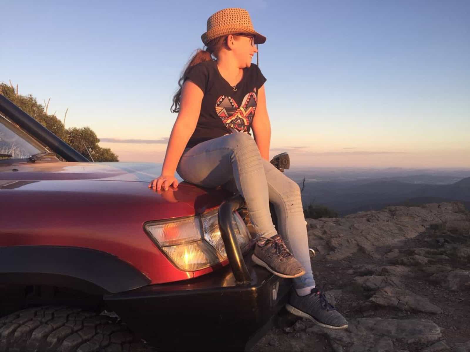 girl looking at sunset in car bonnet