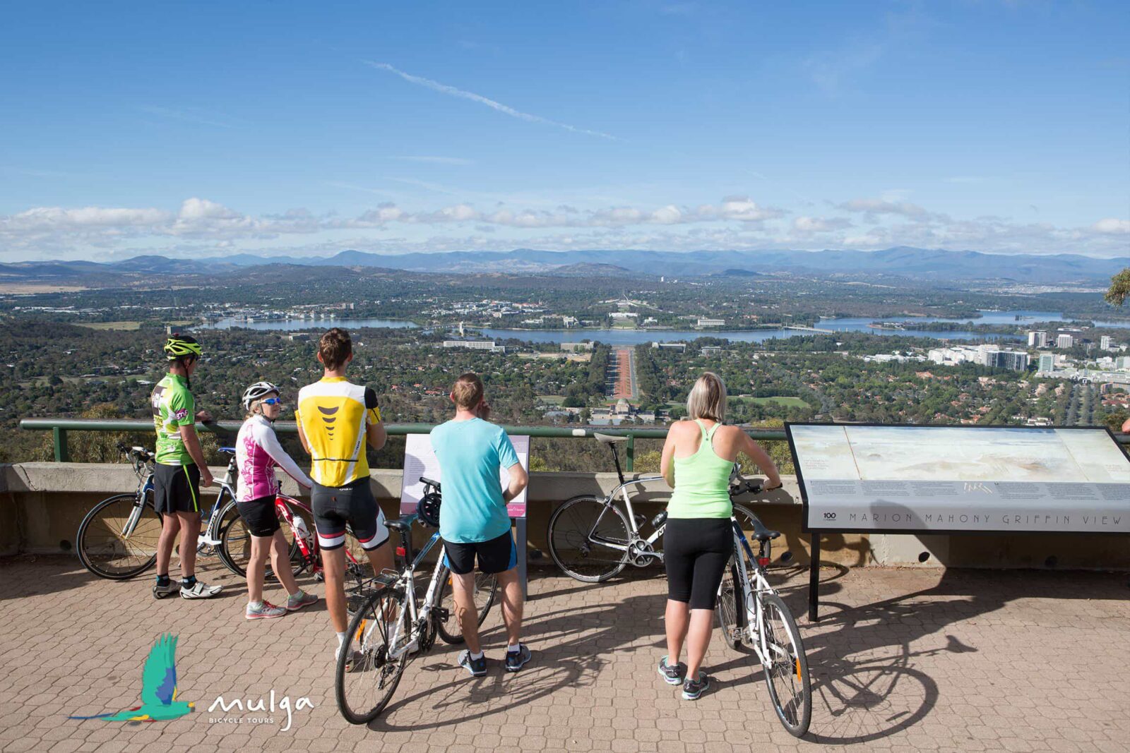 5 cyclists stand with their bikes behind the Marion Mahony Griffin View handrail.