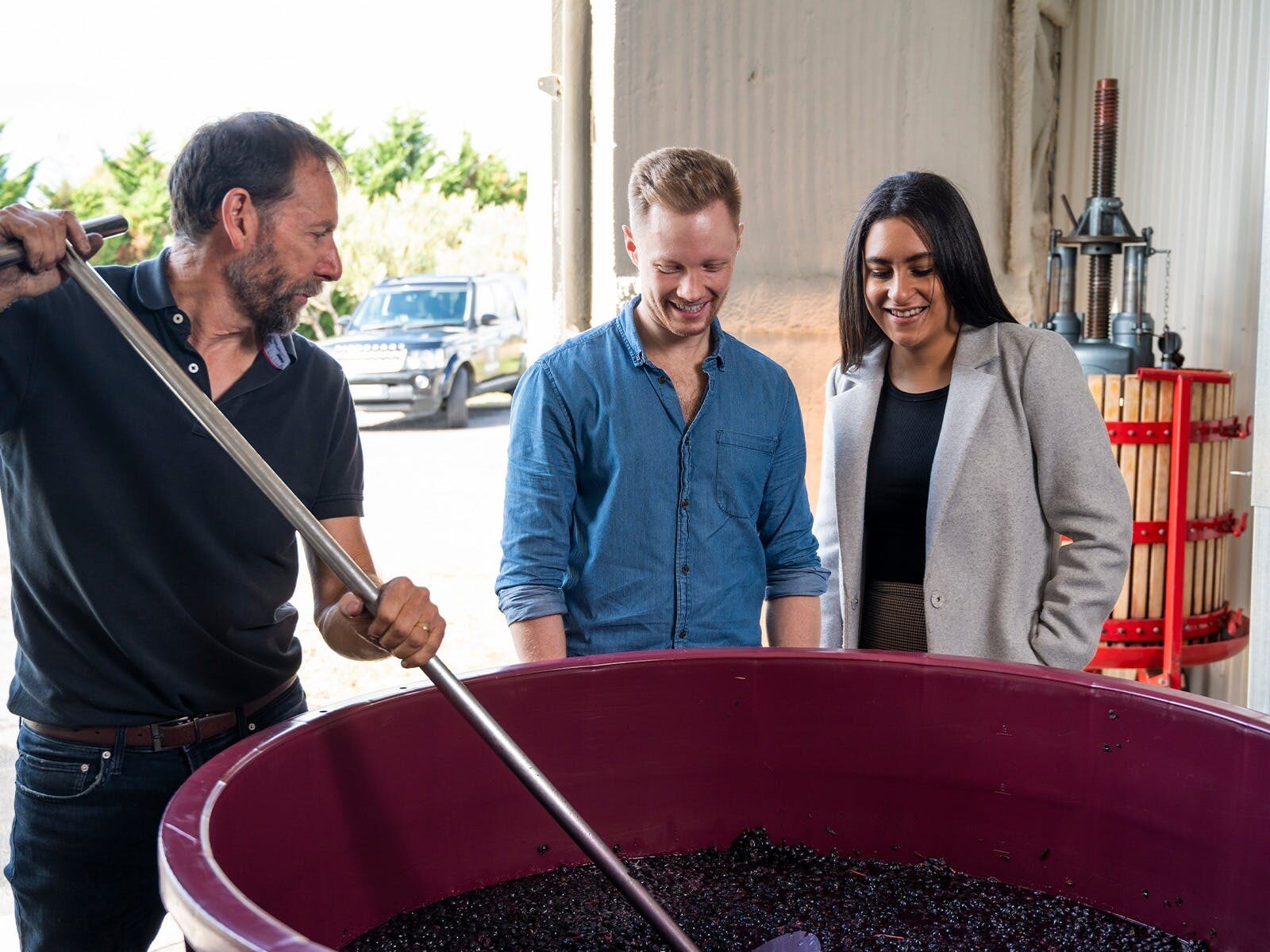 A couple in a Canberra winery looking at fermenting red grapes