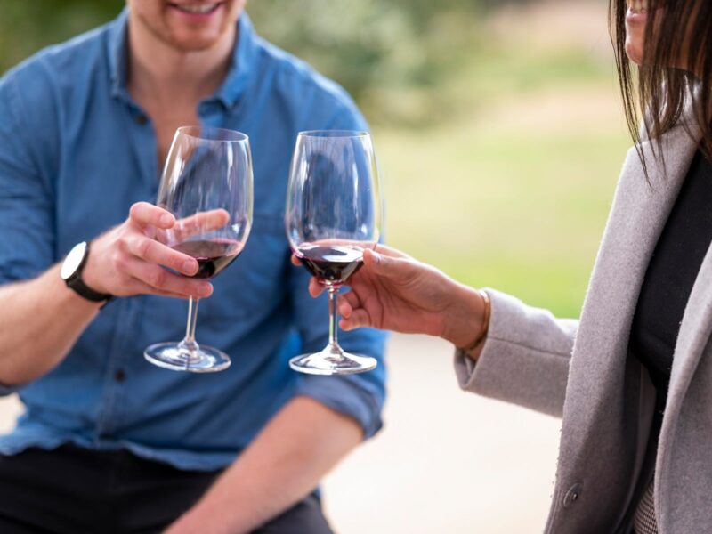 A couple are about to cheers red wine glasses on a wine tasting in Canberra