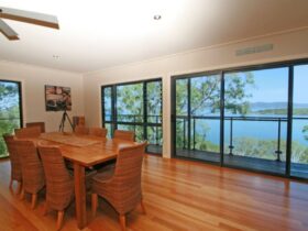 Dining room with 8 seater setting, ceiling fan and ocean views
