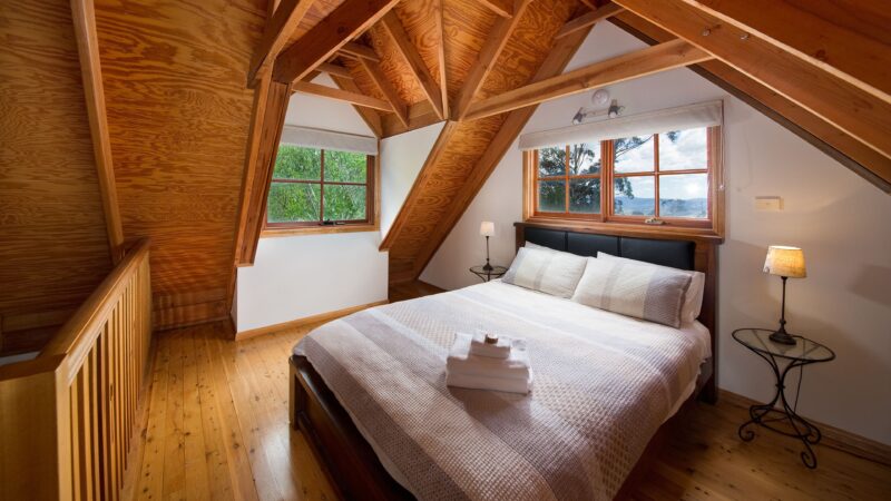 The loft bedroom with distant views of the Kanimbla valley. Classic Blue Mountains cottage style. Premium A.H.Beard Kingcoil queen mattress.