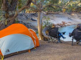 Campers sit next to a tent overlooking the river, Darling River campground, Toorale National Park.