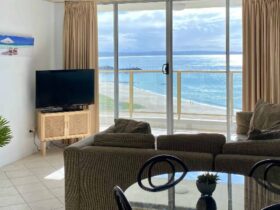 Lounge room with lounges, TV and stunning beach views