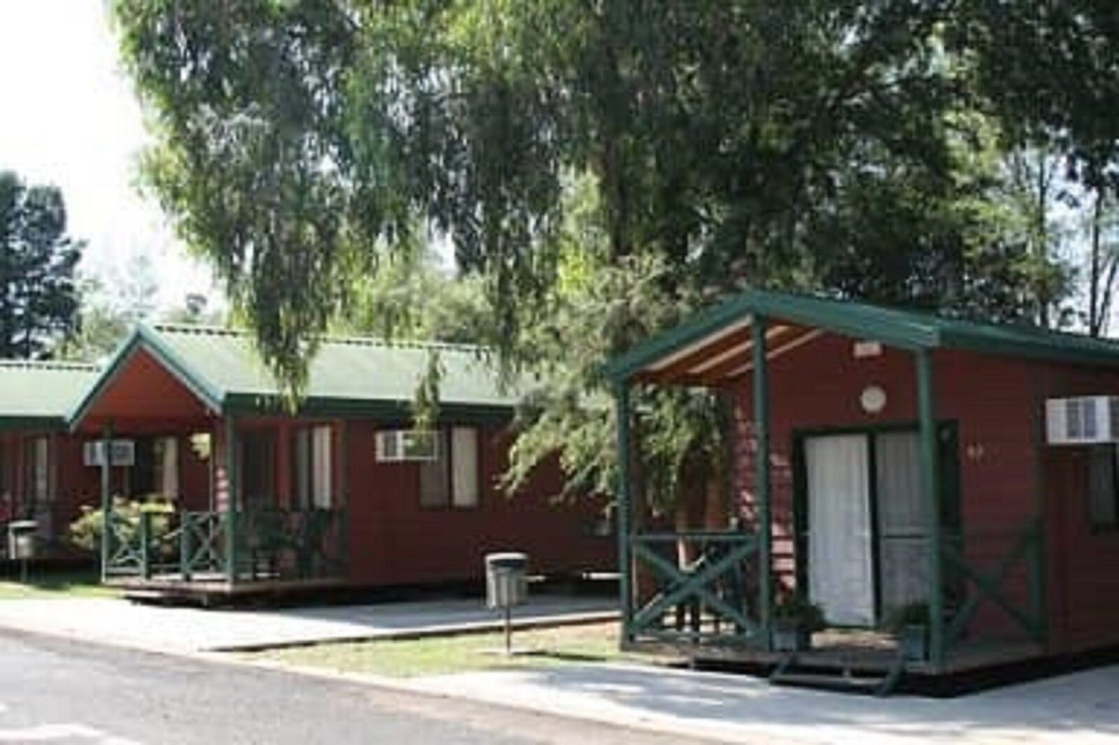 Two Cabins side by side with large shady tree branch hanging over cabin in foreground