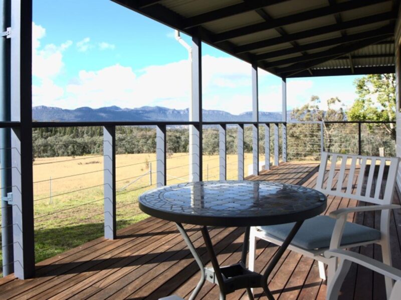 The wrap-around verandah with table and chairs at Honeyeater Homestead looking out to Capertee