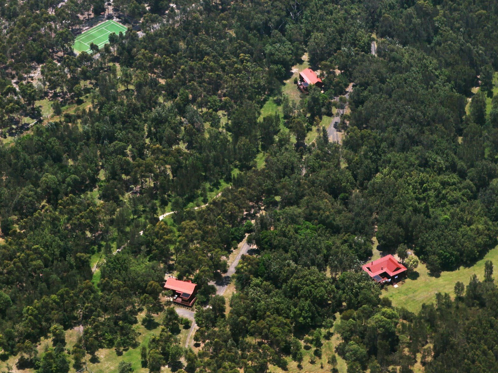 Melaleuca Seaside Retreat - Aerial view of forest, cottages and Tennis/Basketball court.