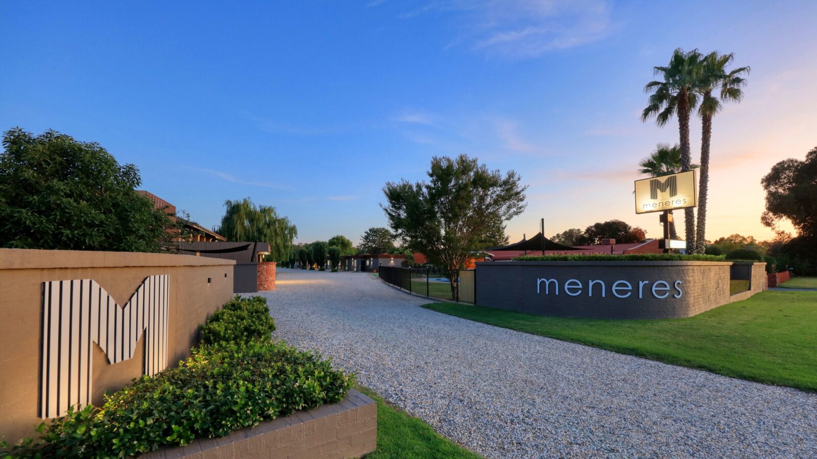 Motel Meneres front entrance at dusk showing rushed rock driveway with rendered brick entry.