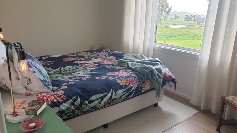 Master Bed, floral sheets and a view of green grass out the window