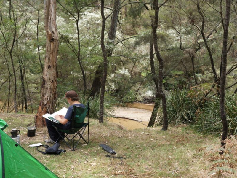Camper relaxing by the river Newnes campground. Credit: Stephen Alton © DPE