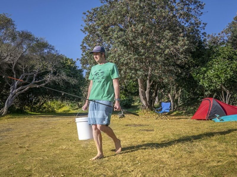 Camper with his fishing rod and bucket heading to the nearby beach, Goolawah National Park. Photo: