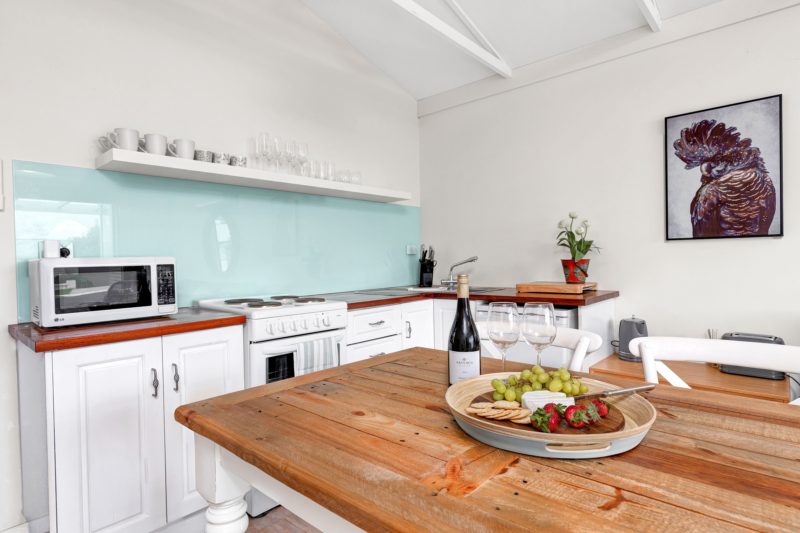 Kitchen with pale blue splashback, oven, microwave white cupboards and dishwasher
