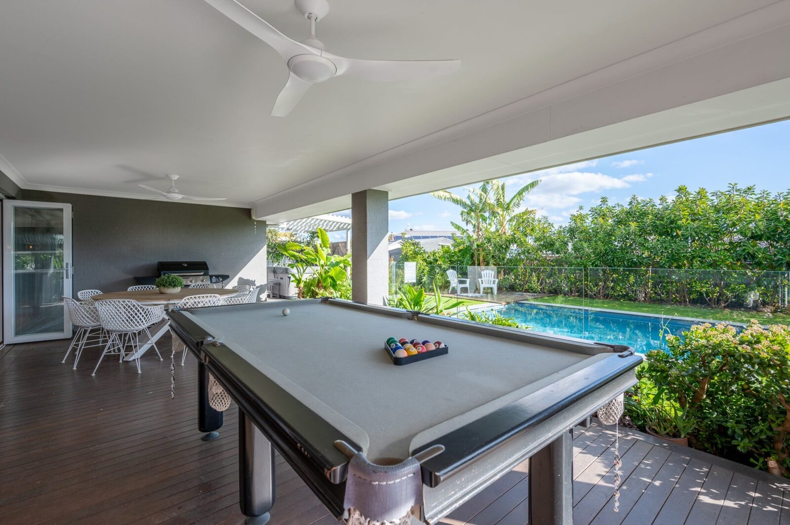 Outdoor entertaining area with BBQ and pool table, next to the pool and spa