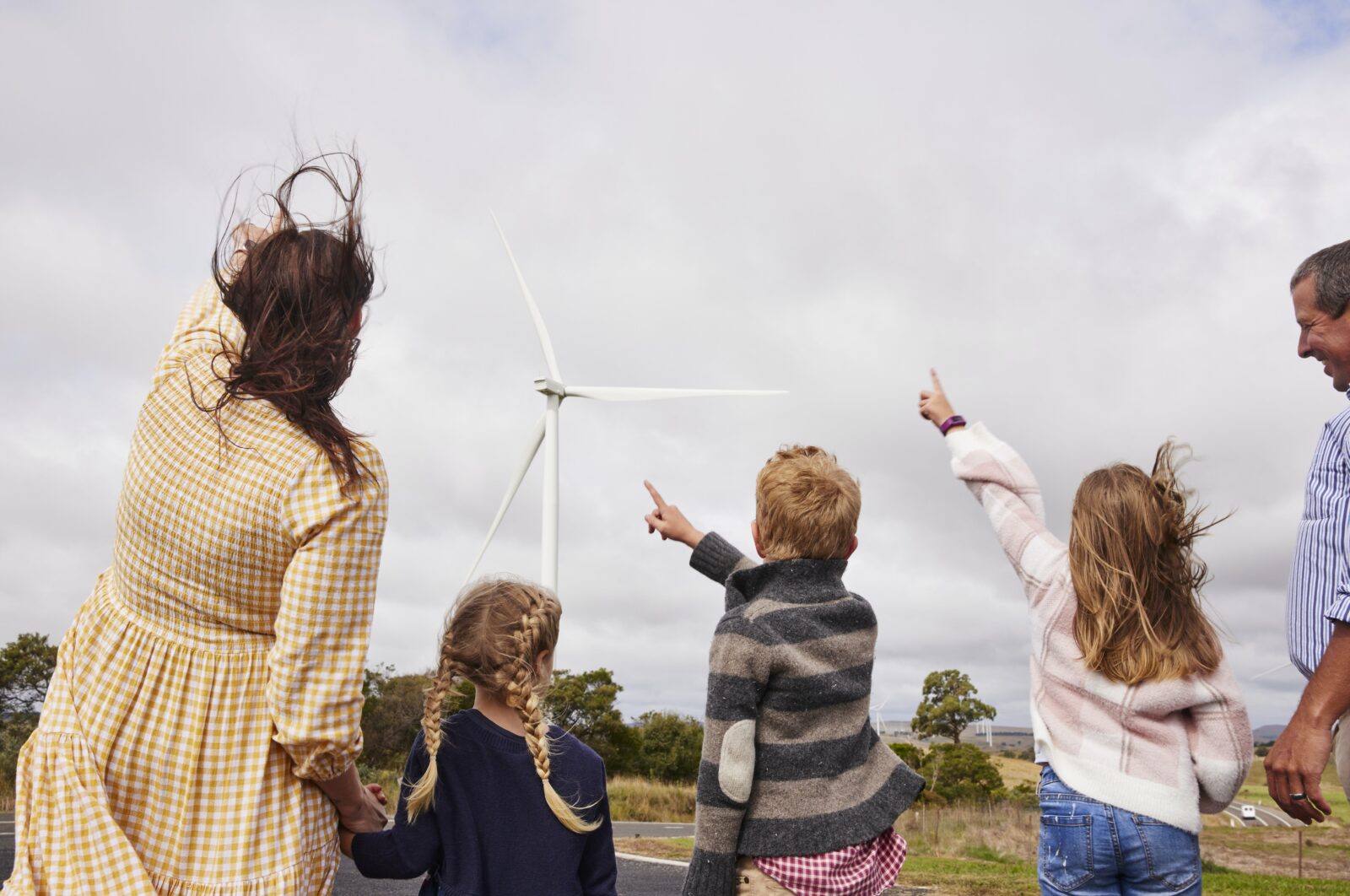 family pointing a large wind turbine