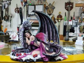 Small statue of a purple fairy sleeping on a dragon.