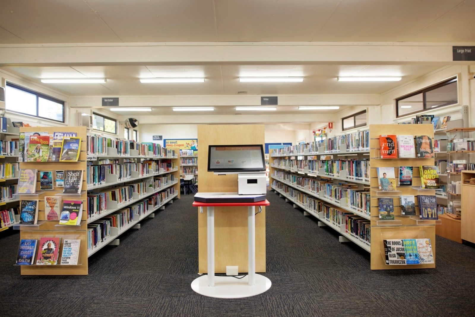 Interior of Helensburgh library with rows of bookshelves and a digital catalogue for searching