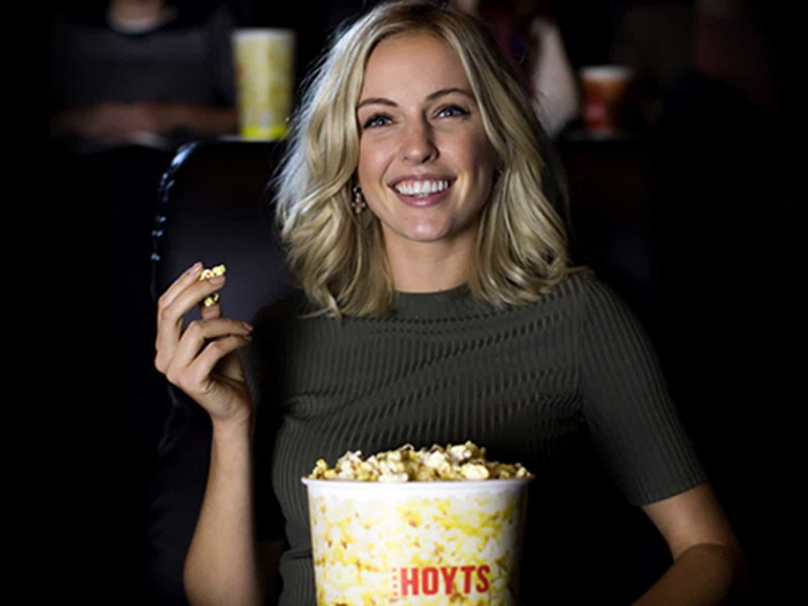 Woman eating popcorn in move theatre