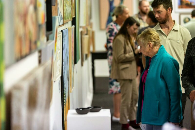 a man and a woman viewing a display of artwork on a wall inside the Art Gallery