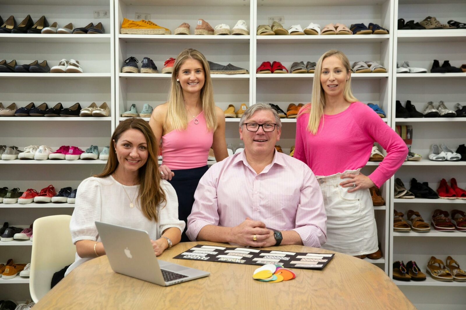 Three women and one man smile in front of shoe displays
