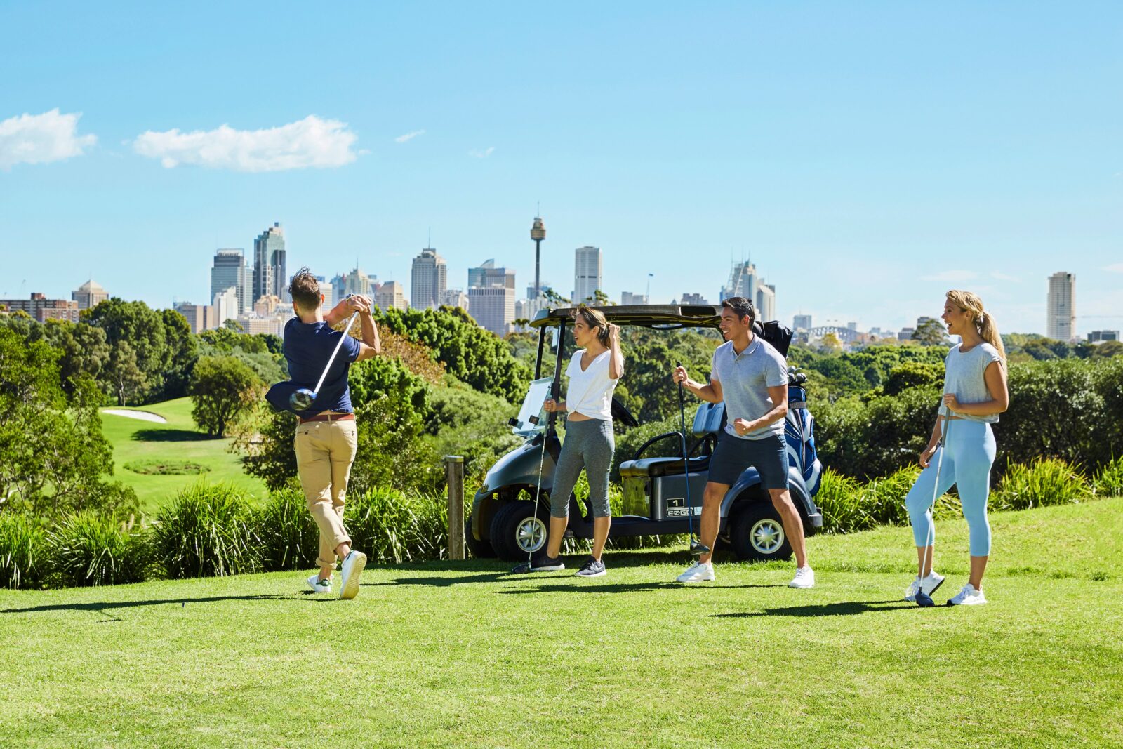 Four people teeing off with Sydney's city skyline in the background