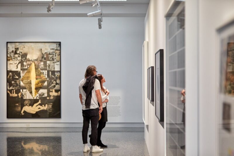 Two visitors view photography in a wide open gallery space