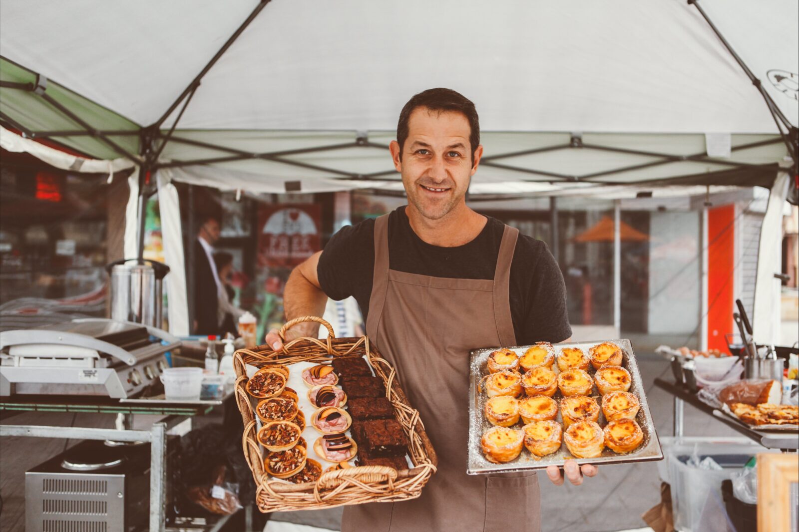 Stallholder from Courtney's Brasserie holding trays of cakes and tarts