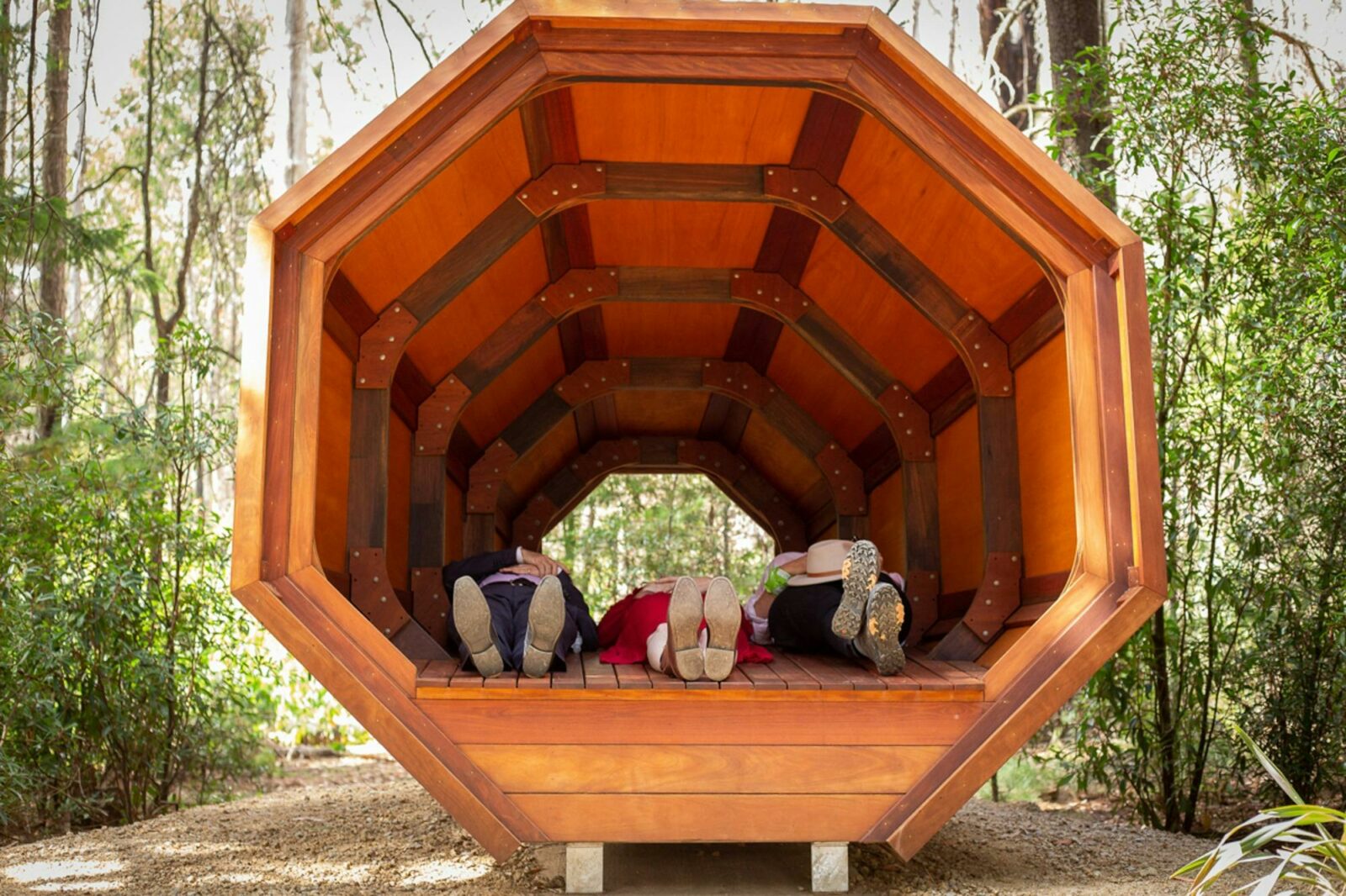 Three pairs of feet are visible in the Sound Pod on the Wellness Walk in Bago State Forest