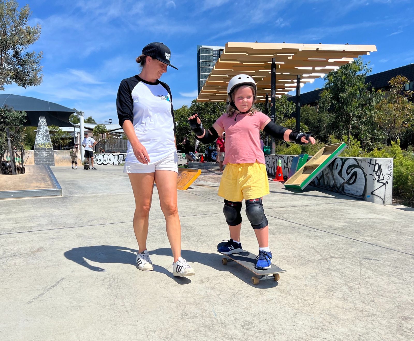 A beginner student guided by her skate instructor whilst learning how to push.