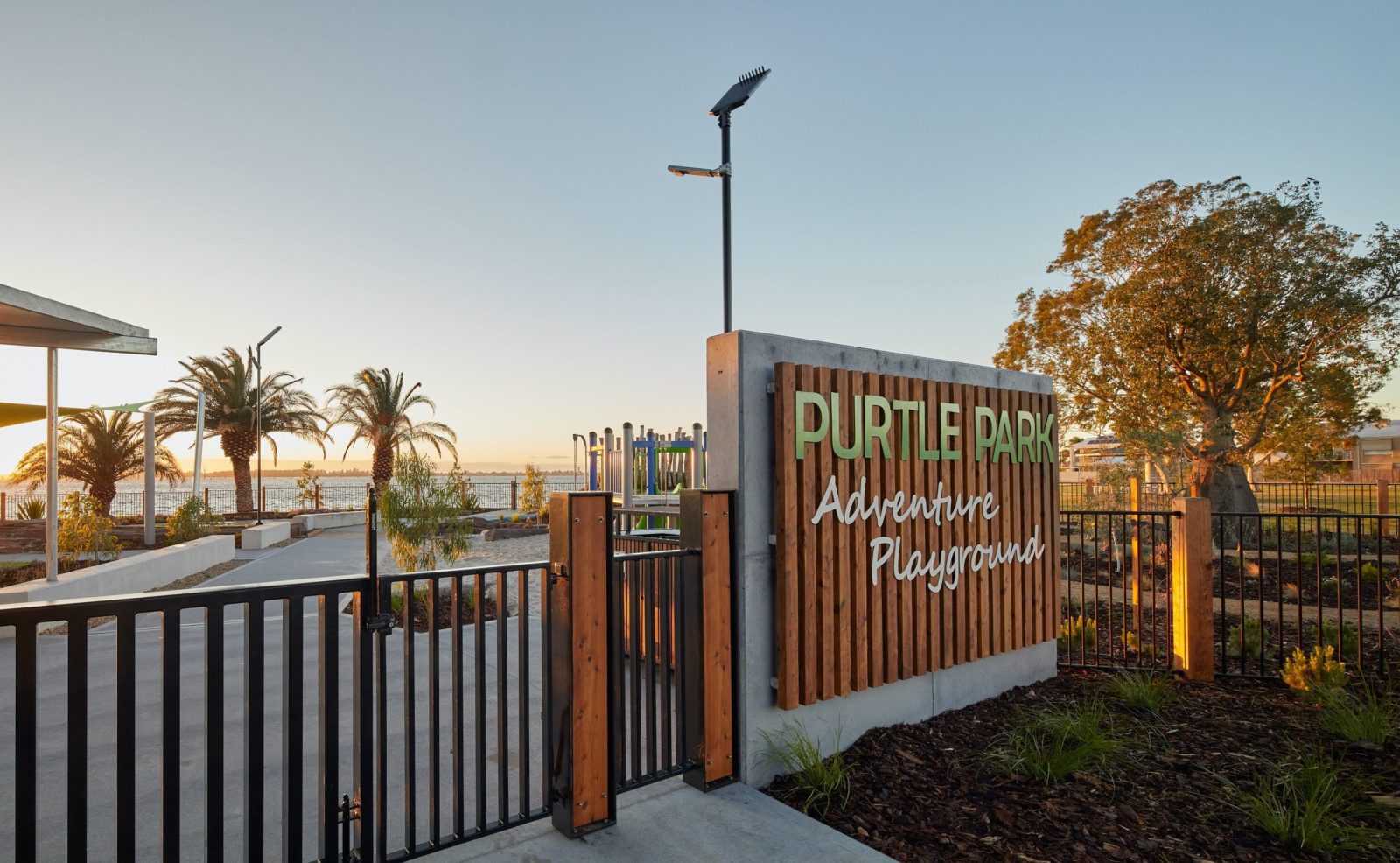 A fence and gate leading to a playground. A sign reads "Purtle Park Adventure Playground".