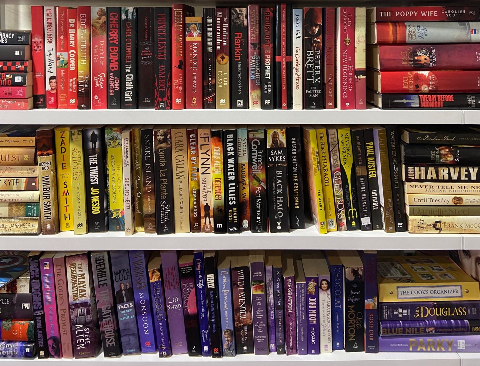 Bookshelf displaying books by colour.