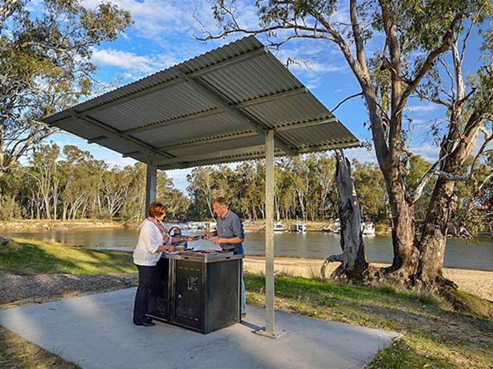 Two people at a barbecue shelter at Ski Beach picnic area, Murray Valley National Park. Photo: Gavin