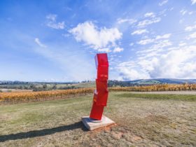 Kinetic Red Sculpture, situated in a picturesque vineyard.