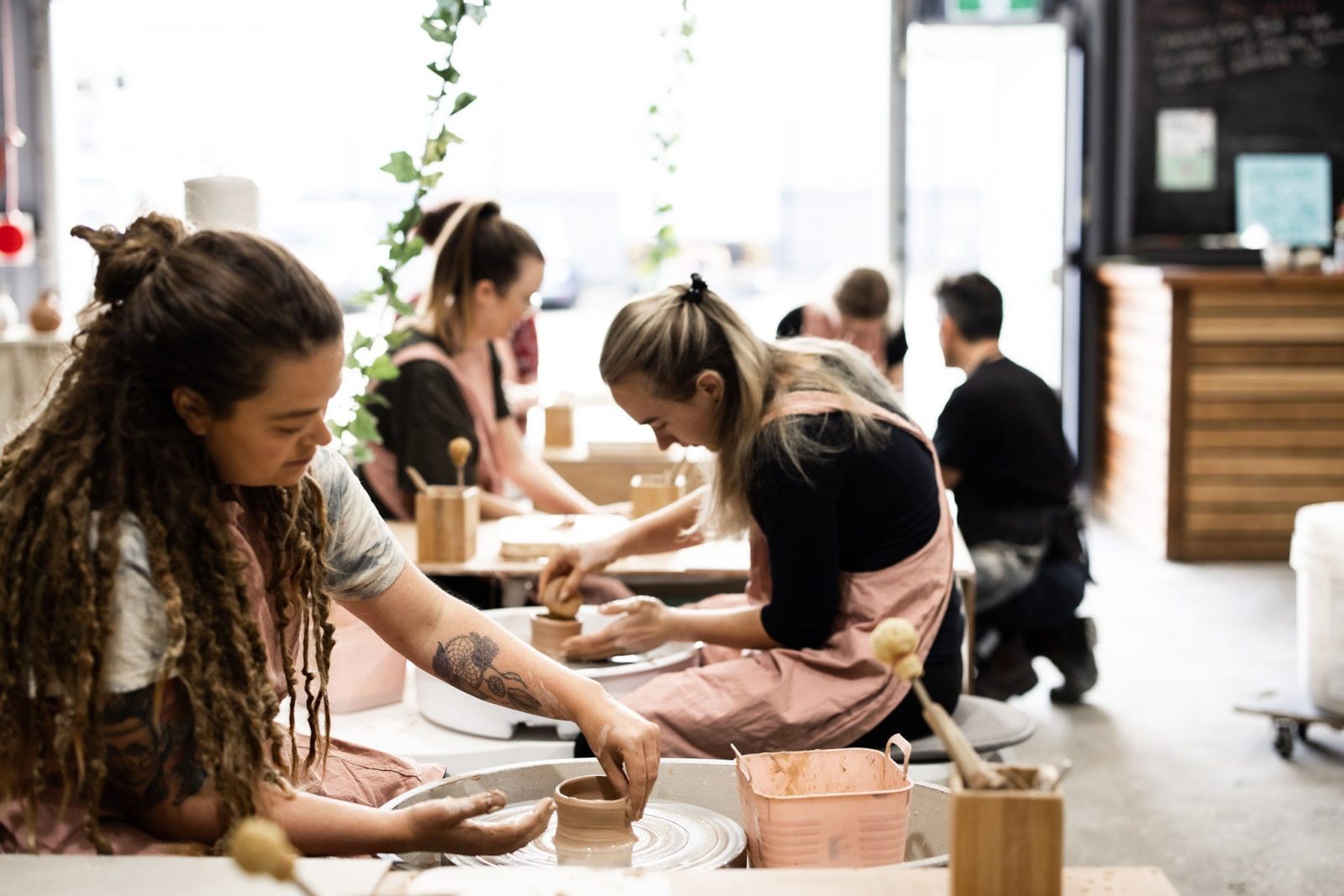 Picture shows a group of people on pottery wheels in a pottery studio