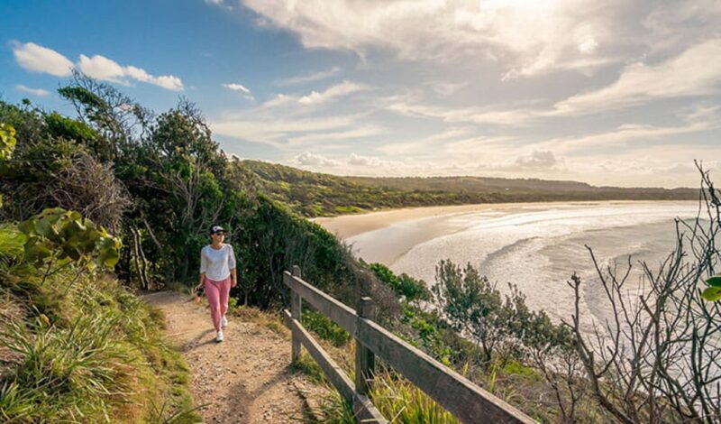 Woman walking along Three Sisters walking track, overlooking the beach in Broken Head Nature Reserve