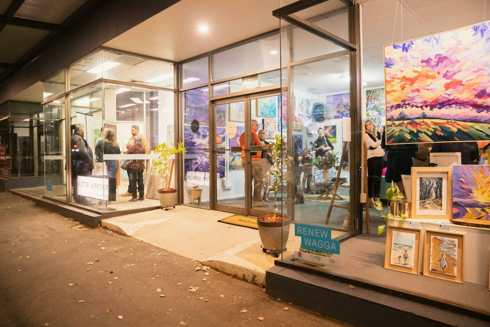An angled photograph from the street of multiple shopfront windows filled with artworks.