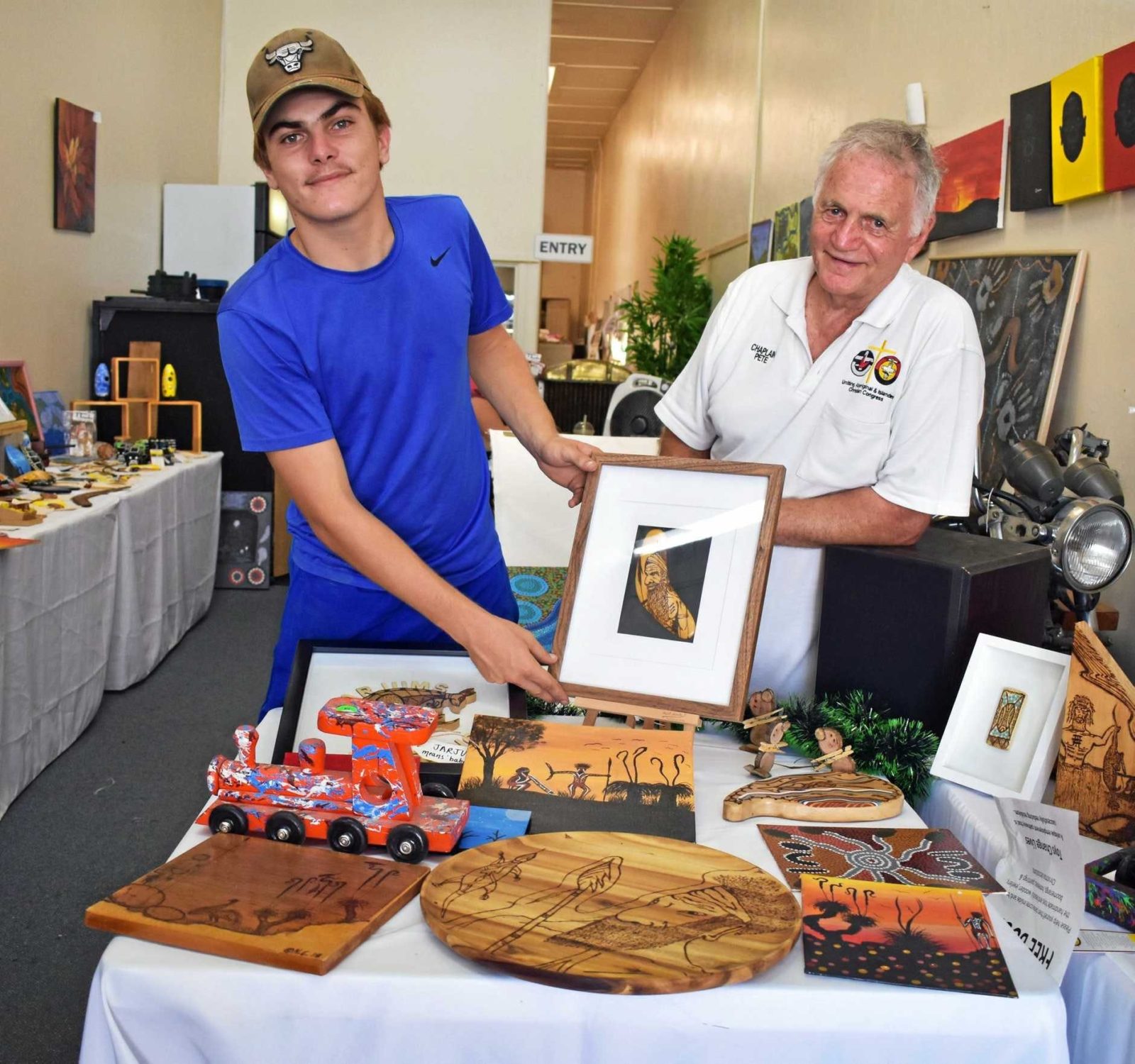 Man and teenage boy displaying local Aboriginal art.