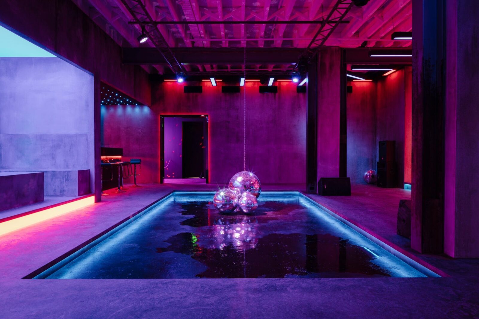 An artwork installation of a dancehall with neon club lighting and disco balls on the floor
