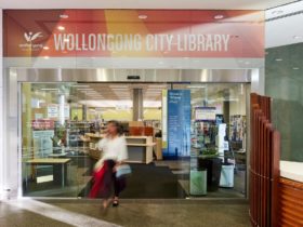 A woman walking out of the Wollongong Library front doors into a foyer.