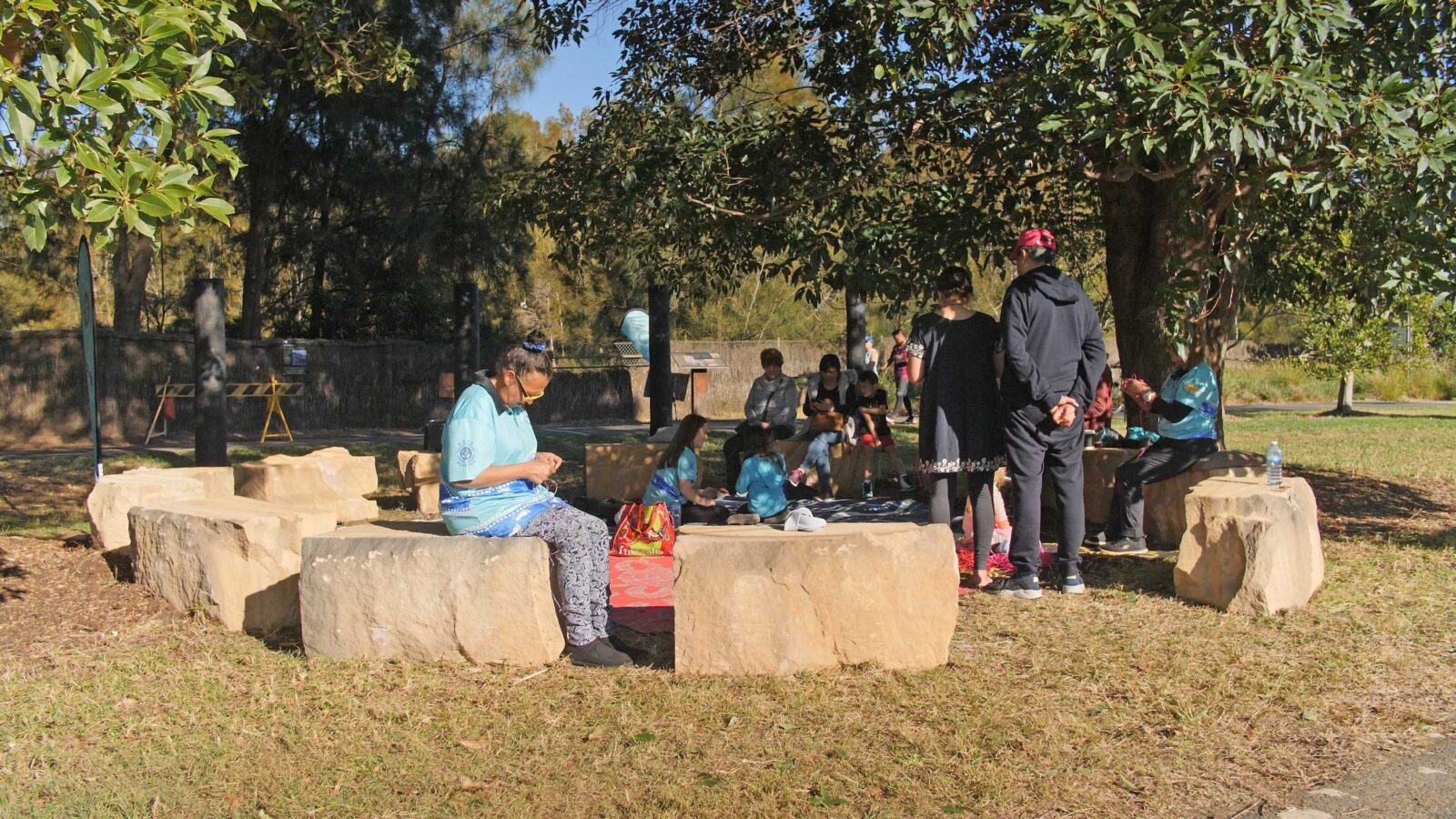 People seated around yarning circle of sandstone blocks.