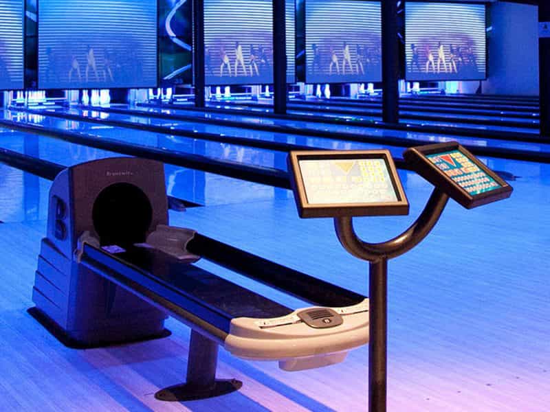 Ball return and bowling lanes lit in blue light
