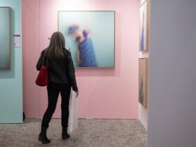 Women standing facing art on pink wall