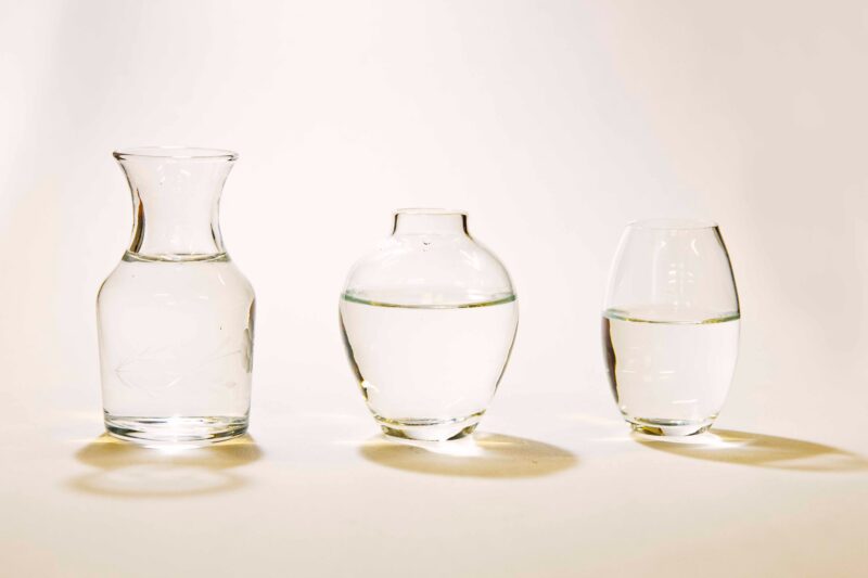 3 small vases with water in them with a white background