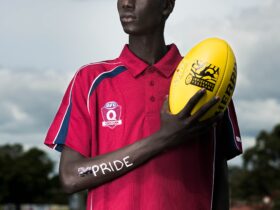 photo shows a young male refugee holding an australian rules football