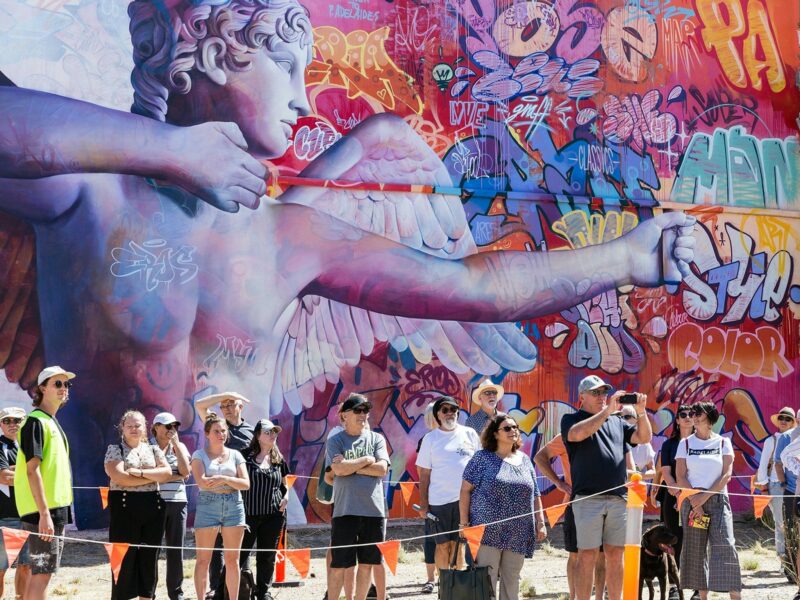 Various people standing in front of a massive mural
