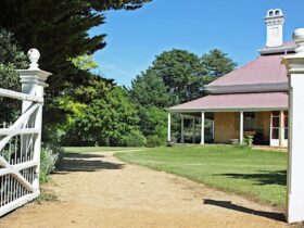 White gate is open to historic Bedervale, an 1842 house that lies at the end of a sandy gravel drive