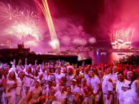 Fireworks over Sydney Opera House and Harbour Bridge with crowd dressed in white in foreground