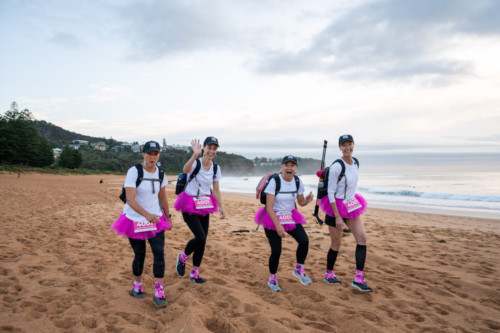 a team of women walking on the beach in tutus