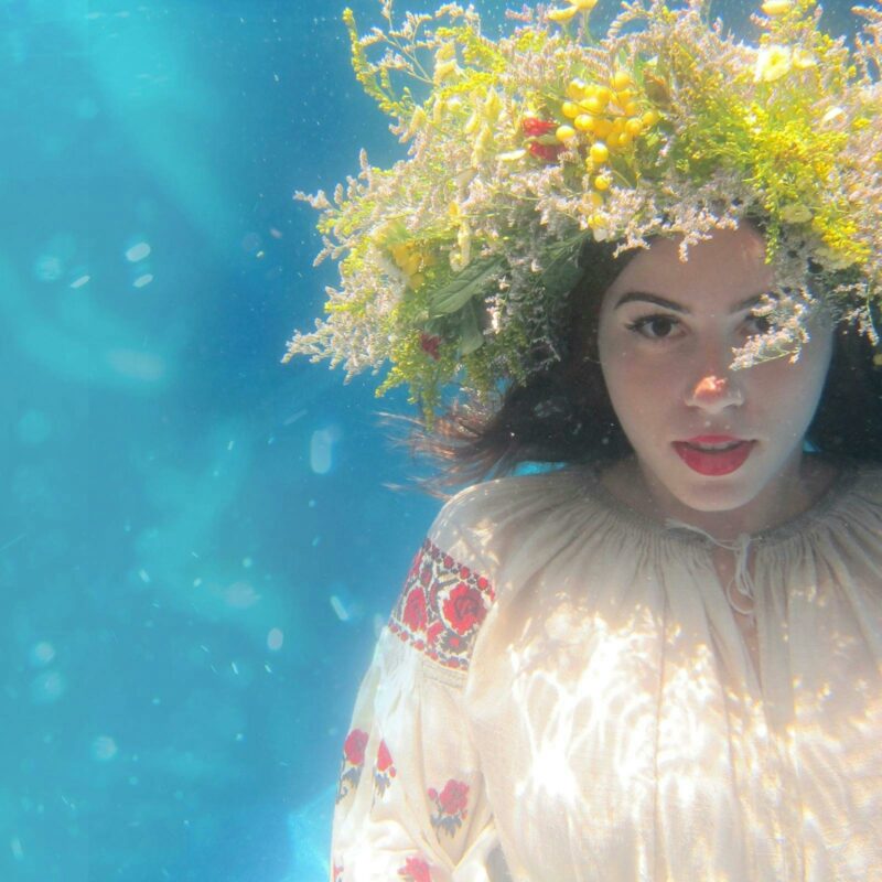 A Ukrainian girl looks towards the camera, floating underwater.