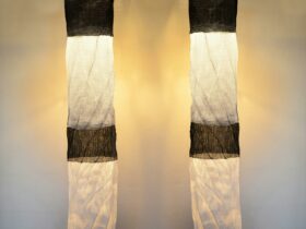 Two illuminated black-and-white textile cylinders hang suspended from the ceiling.